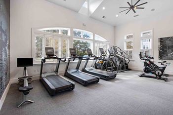 a gym with cardio equipment and windows in a building